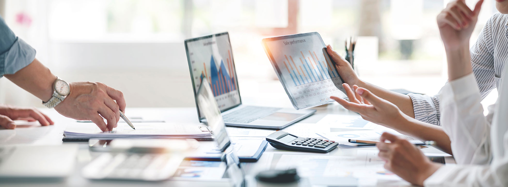 People working at a table on computers showing charts and graphs.